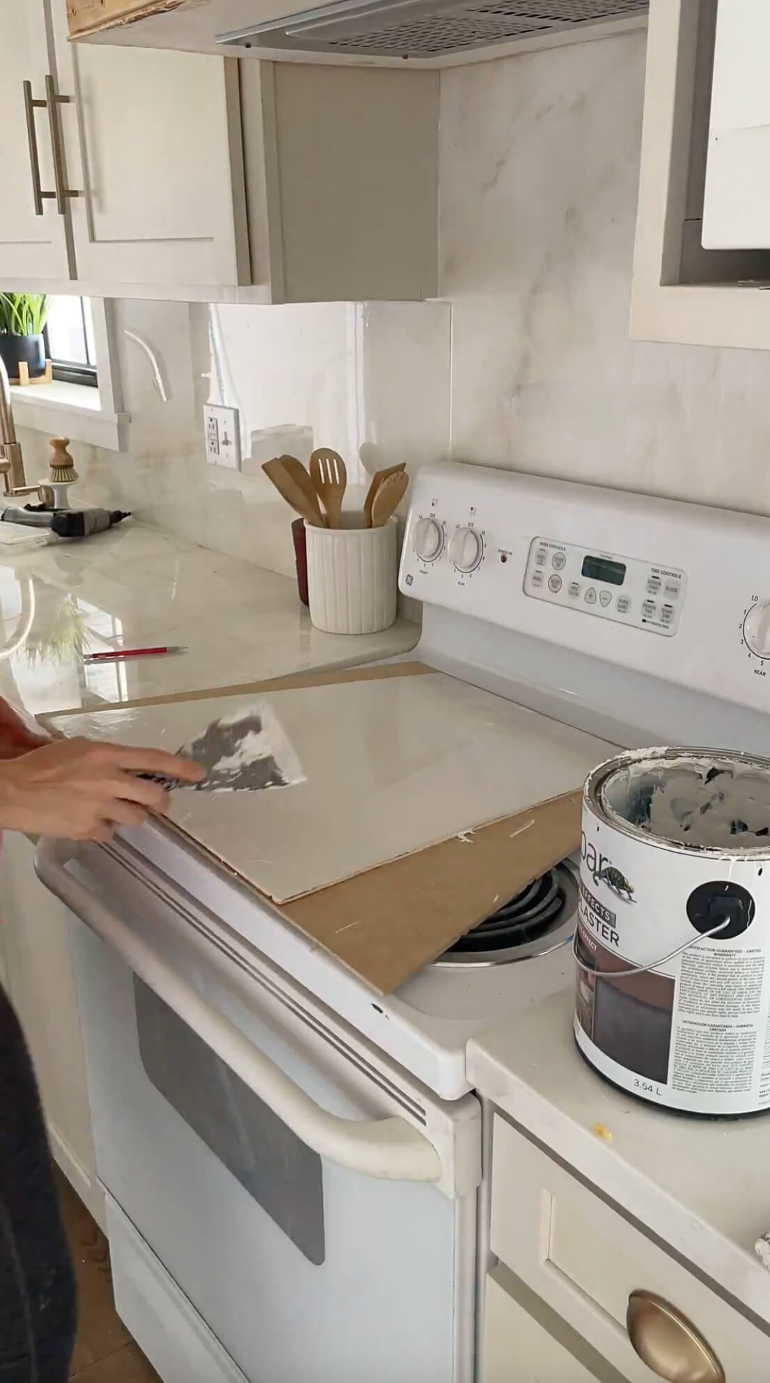 Using a putty knife to apply venetian plaster to a DIY range hood.